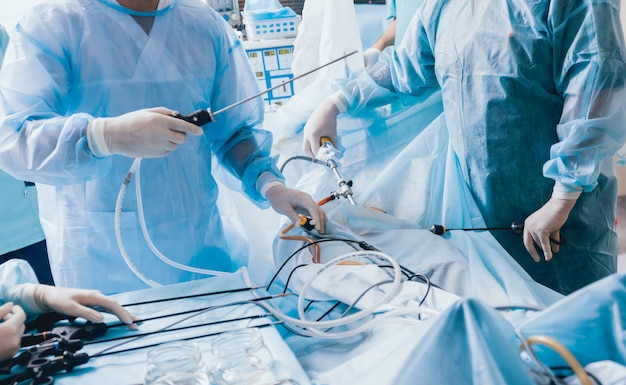 Process of gynecological surgery operation using laparoscopic equipment. Group of surgeons in operating room with surgery equipment