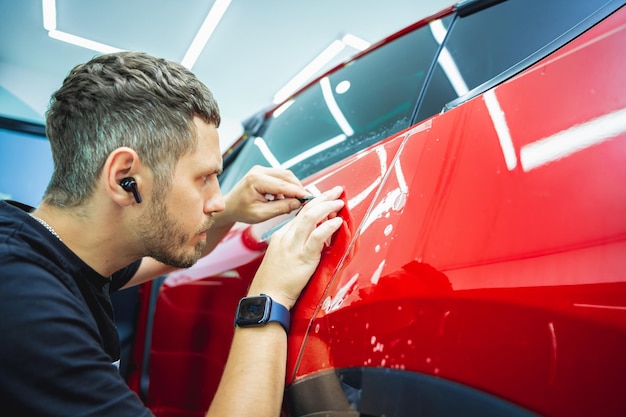 The process of installing protective film on the new red car