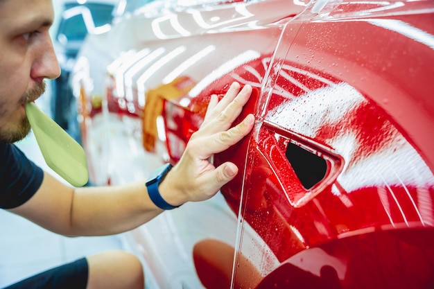 The process of installing protective film on the new red car