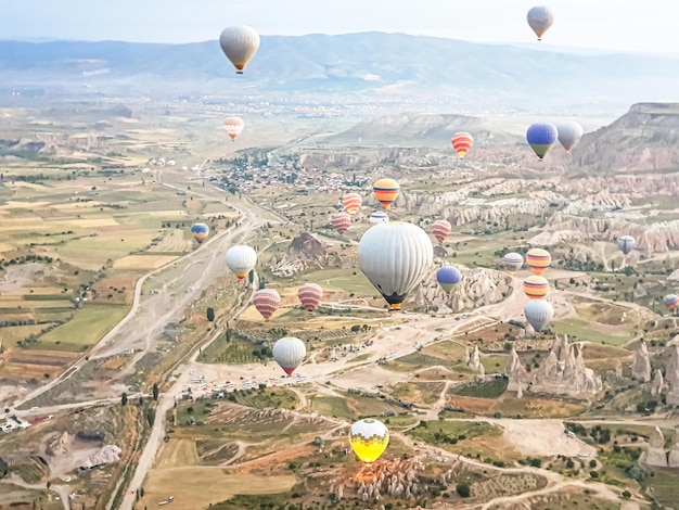 Photo process of launching many colored beautiful balloons into air in cappadocia in mountains early at dawn filling balloon with hot air from burner preparing basket excursionflight for tourists above