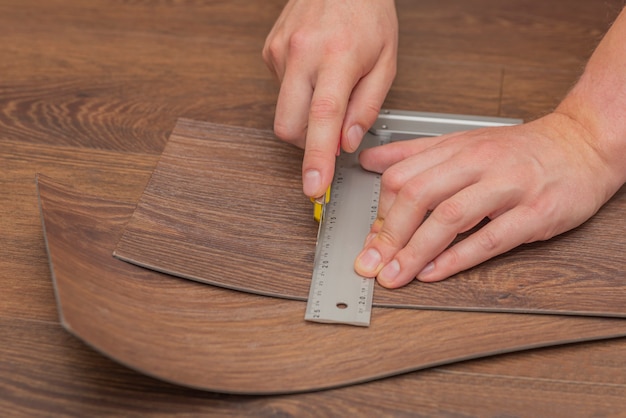 The process of laying vinyl flooring in public places, cutting brown vinyl floors. Resistant floors in common areas.