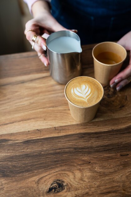 The process of making a barista cappuccino with a beautiful pattern on the foam in an ecocraft glass Coffee to go concept