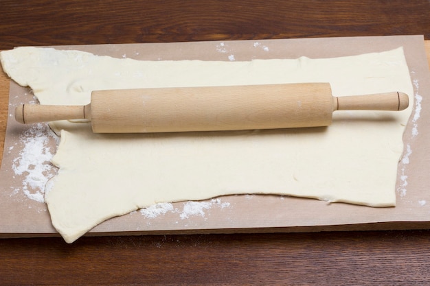 Process of making cooking pasta. Rolling pin on rolled dough