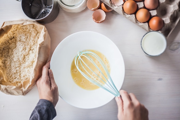 Process of making the dough, woman's hand whips eggs and flour in bowl