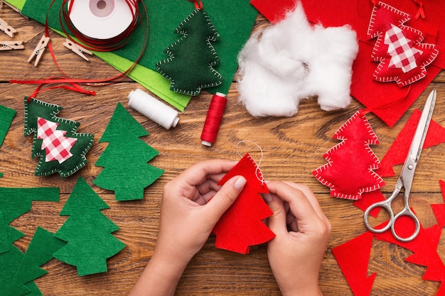 Foto processo di realizzazione di peluche fatti a mano, decorazioni per cucire con feltro e ago per l'albero di natale, vista dall'alto