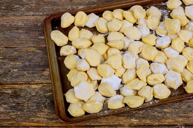 Process of making homemade pelmeni dumplings on wooden board - traditional ukrainian cuisine.