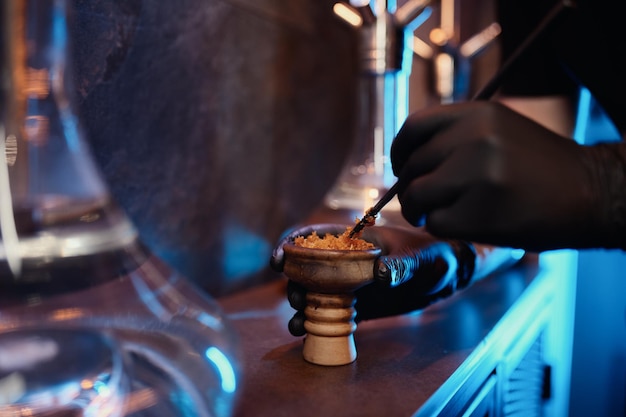 Process of making hookah for smoking. Closeup view on shisha man preparing tobacco in bowl