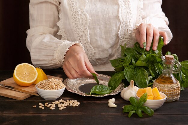 The process of making pesto sauce at home. A woman plucks leaves from a basil branch.