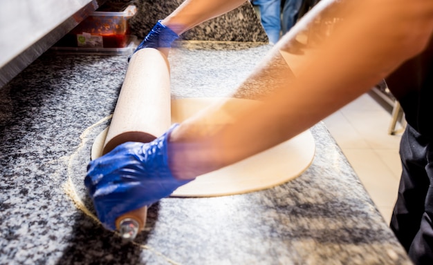 The process of making pizza. Hands of chef baker making pizza at cafe kitchen