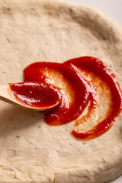 Process of making pizza, tomato sauce on a dough