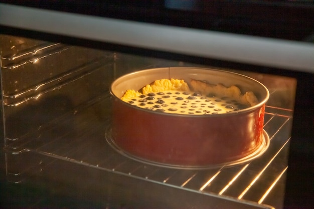 Procedimento di preparazione della torta rustica di pasta frolla con mirtilli in panna acida che si riempie in una teglia in forno.