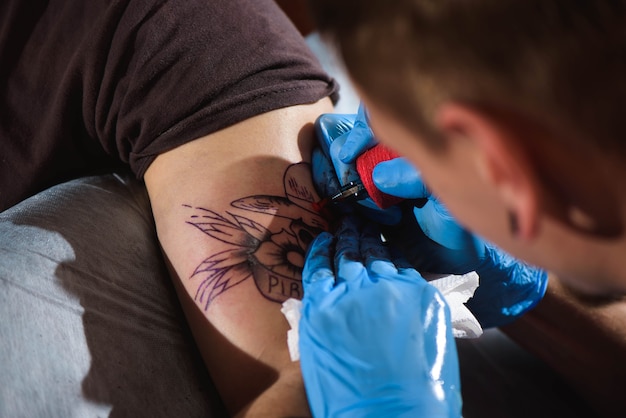 Process of making tattoo close-up, man creating picture on hand with it in salon