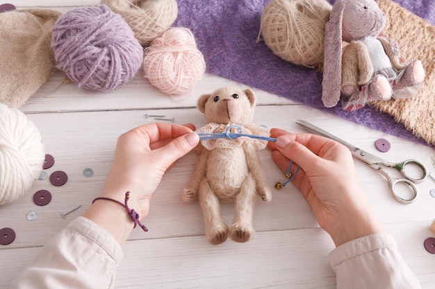 Process of making vintage toy, top view. Artisan pov, needlewoman hands sewing handmade teddy bear, home workshop