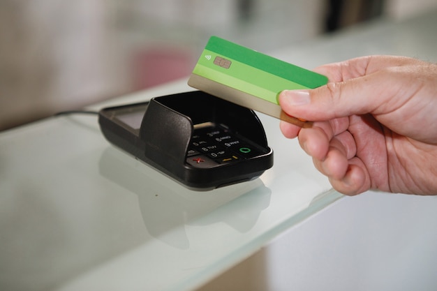 The process of paying with a contactless bank card with a plastic card in the store terminal.