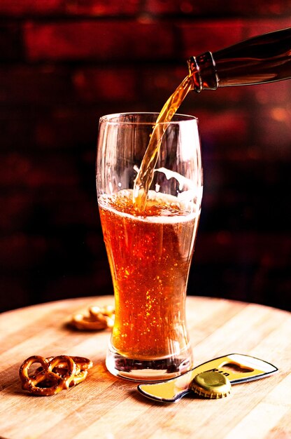 Process of pouring amber beer into the glass on a wooden board and snacks