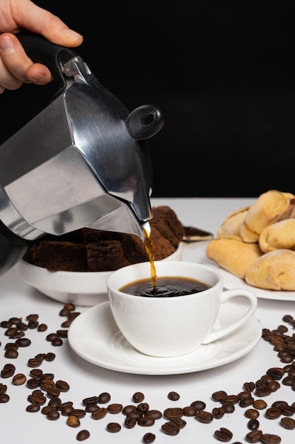 Photo the process of pouring coffee from a geyser moka coffee maker into a white cup