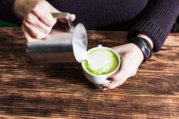 Foto processo di versare il latte nella tazza di tè matcha