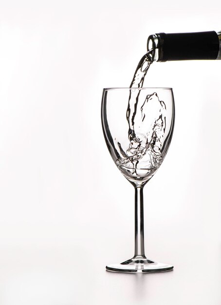 Photo the process of pouring wine into a glass on a white background a large space for text on the left