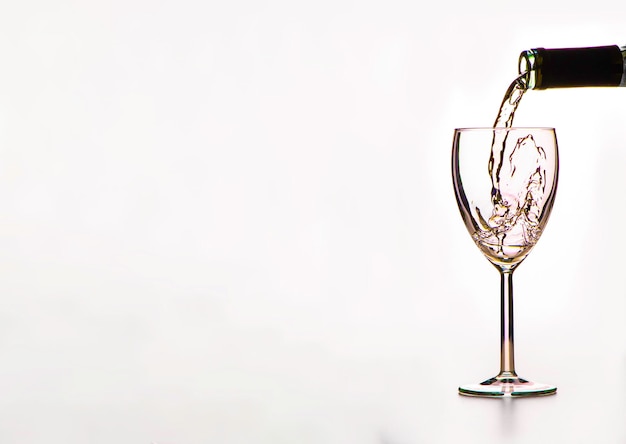 The process of pouring wine into a glass on a white background a large space for text on the left