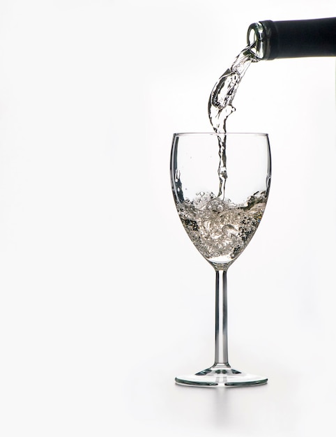 Photo the process of pouring wine into a glass on a white background a large space for text on the left