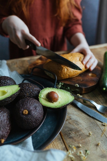 Il processo di preparazione di una sana colazione a base di pane e avocado su un tavolo di legno.