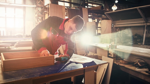 Process of production and manufacture of wooden furniture in
furniture factory worker carpenter man in overalls processes wood
on special equipment