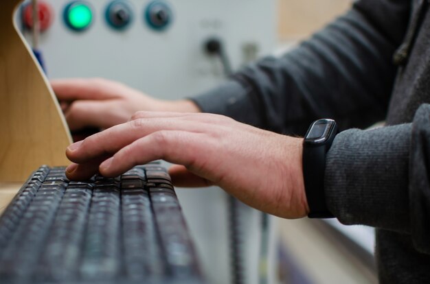 The process of programming a CNC machine. Entering data into a computer controlled machine, starting CNC engraving, control screen. Furniture manufacturing.