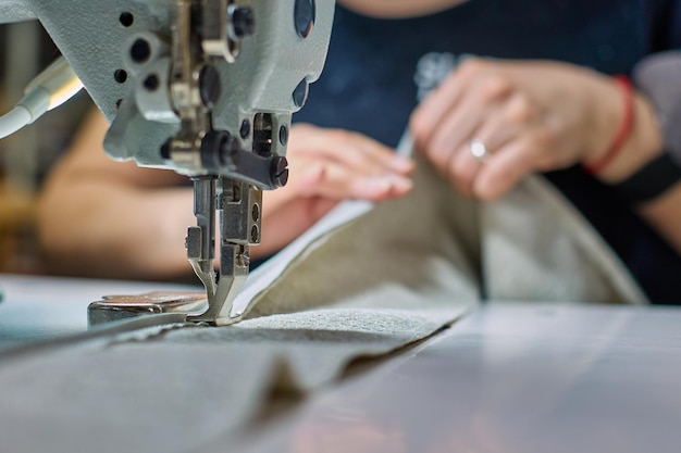 Process of a seamstress sewing beige fabric in a sewing workshop