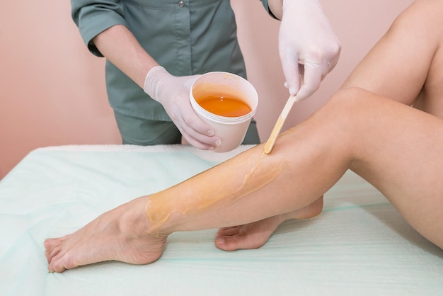 The process of shugaring legs in a beauty salon The concept of grooming the case removing unwanted hair