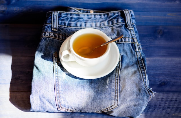 Process tea brewing in ceramic mug Herbal green or black whole leaf Healthy habits Tea time concept Cup mug hot water and bag of tea Mug filled boiling water and tea bag on blue jeans background