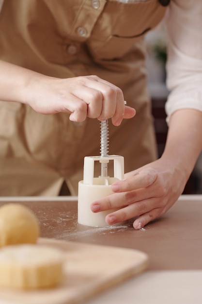 Процесс женщины лепки лунных пирожных с различными начинками с помощью пластикового инструмента