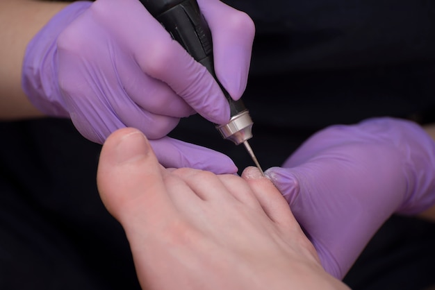 Processing toenails, pedicure. Gloved hands with a pedicure cutter. Close-up