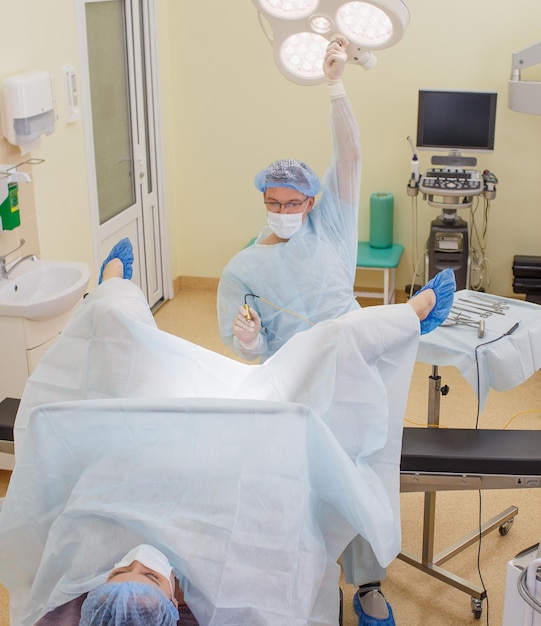 A proctologist examines a patient lying on a proctological chair in the treatment room