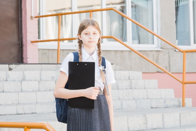 製品広告。あなたの製品を提示する幸せな小さな学齢期の子供。笑顔で製品やサービスを提示する本を持つ少女。あなたはこの製品で間違いを犯すことは決してありません。