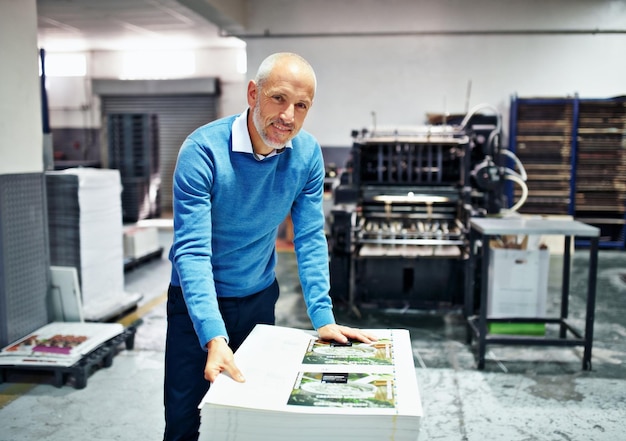 Photo the product is my reputation portrait of a man checking the quality of a print run in a factory