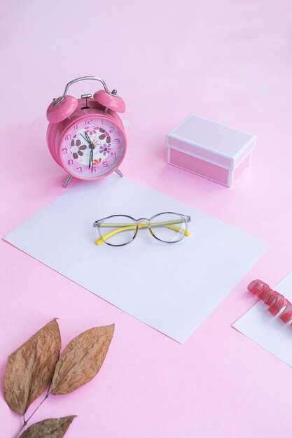 Product Presentation of Minimalist Concept Idea glasses gift box clock and dry leaves on pink paper background