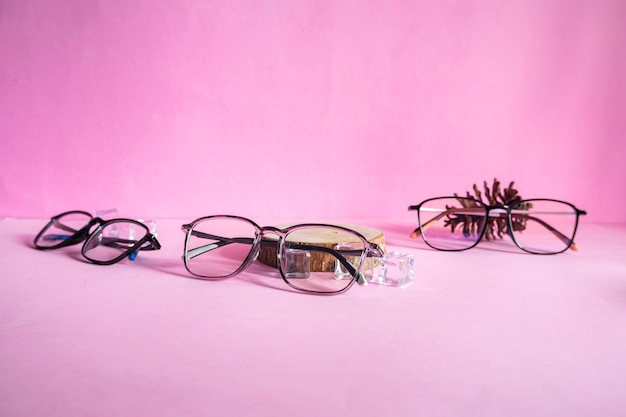 미니멀리즘 컨셉 아이디어의 제품 프레젠테이션. 안경, 통나무, 얼음 조각, 그리고 분홍색 종이 바탕에 소나무 꽃.
