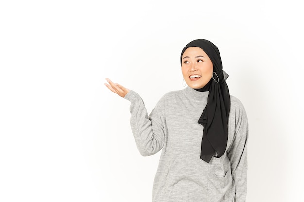 Product presenteren op de palm van mooie Aziatische vrouw die hijab draagt, geïsoleerd op een witte achtergrond