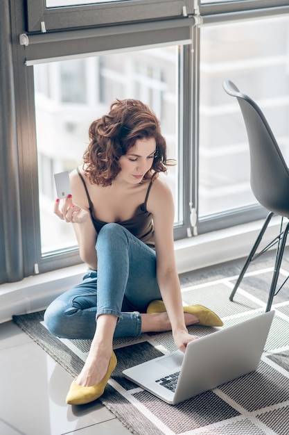 Productief zijn. Donkerharige mooie vrouw die op laptop werkt en tevreden kijkt