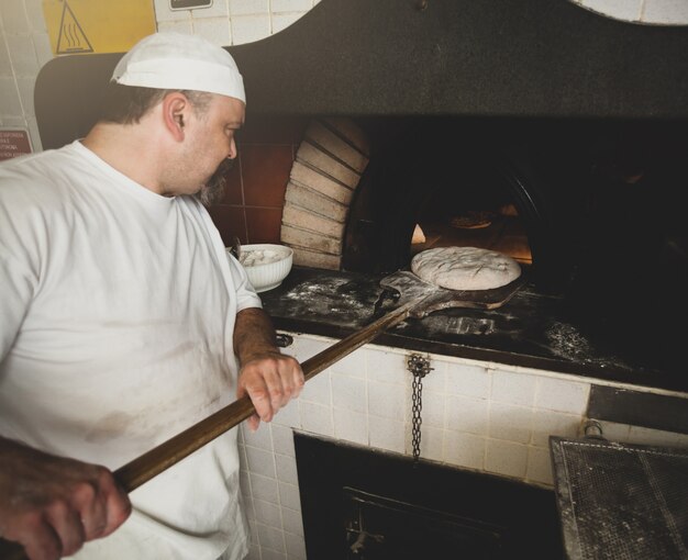 Production of baked bread with a wood oven in a bakery.