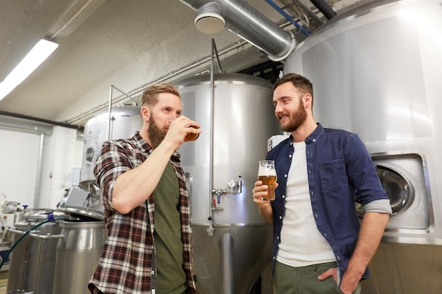 Photo production, manufacture, business and people concept - men testing and drinking non-alcoholic or craft beer at brewery