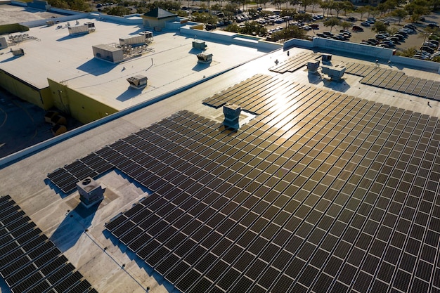 写真 持続可能なエネルギーの生産 緑のエコロジカルな電気を生産するために産業ビルの屋根に装着された青い光電パネルを持つ太陽光発電所の空中写真