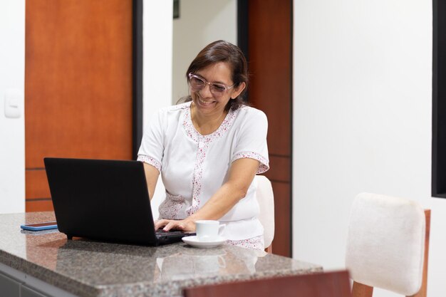 Productiviteit vanuit huis lachende vrouw werkt met haar laptop in haar pyjama
