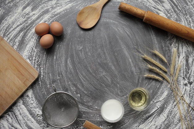 Products for baking bread and cake on a gray concrete table chicken egg, flour, olive oil and milk.