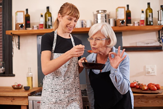 Proef altijd je eten, zeggen ze. Shot van een oudere vrouw en een jongere vrouw die samen koken