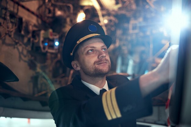 Photo profesol confident pilot is checking plane in hangar