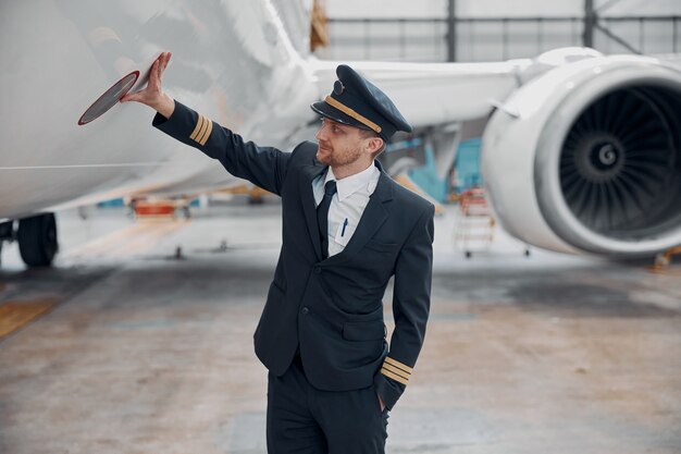 Profesol zelfverzekerde piloot controleert vliegtuig in hangar