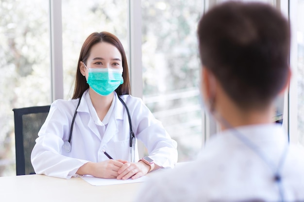 Profession Asian beautiful woman doctor talking with a man patient about his pain and symptom