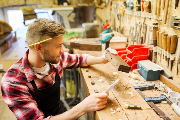 profession, carpentry, woodwork and people concept - carpenter working with wood plank at workshop