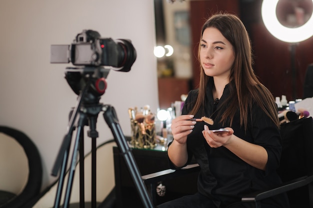 Женщина-визажист профессии, просматривающая косметические продукты на видео-блоге в студии красоты. Женщина